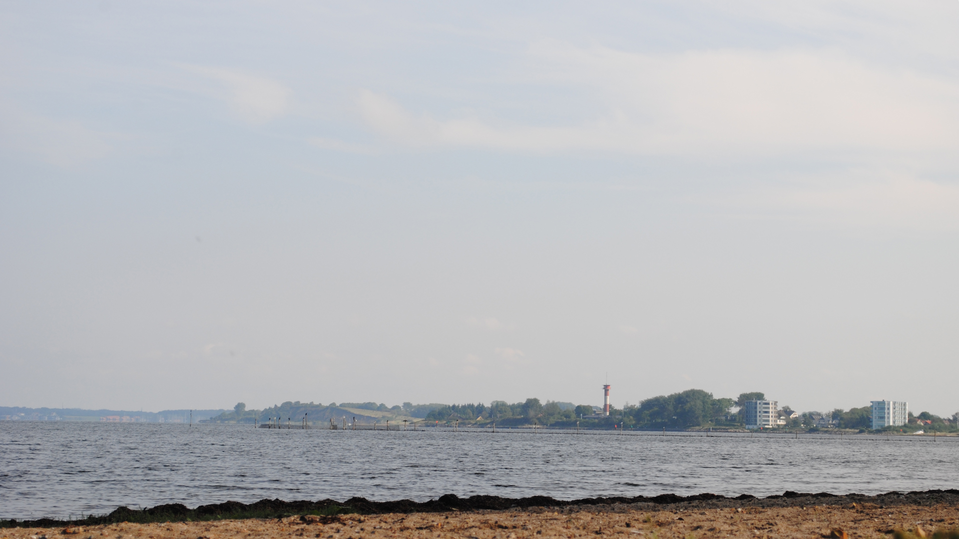 Sie blicken vom Sandstrand aus auf das Gebäude, in dem die Ferienwohnung Fiedler liegt, nicht weit entfernt ist der Leuchtturm.