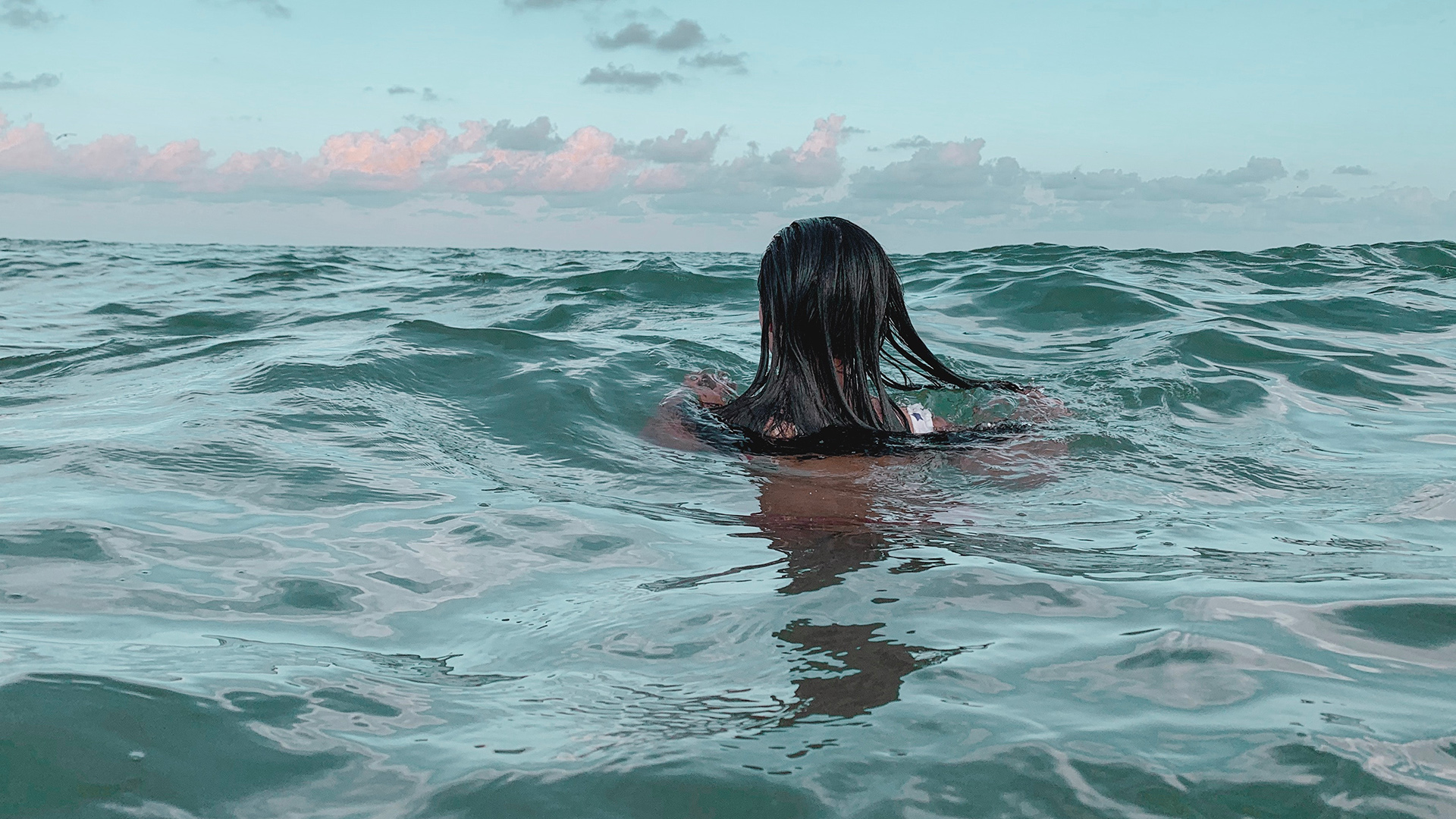 Eine junge Frau schwimmt im Meer.