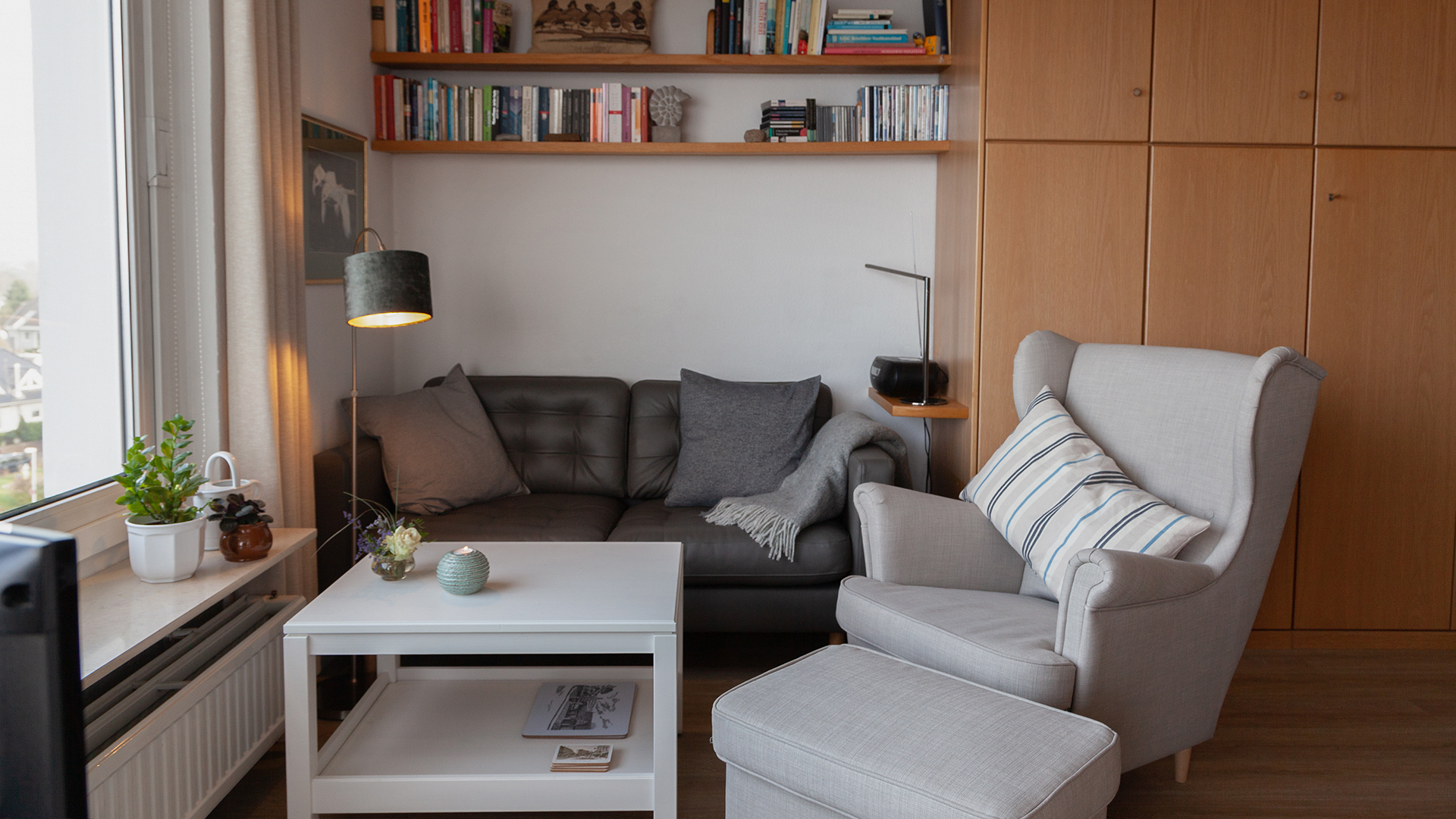 Der Wohnbereich der Ferienwohnung Fiedler mit seinem Zweier-Sofa und dem gemütlichen Ohrensessel mit Hocker dazu.